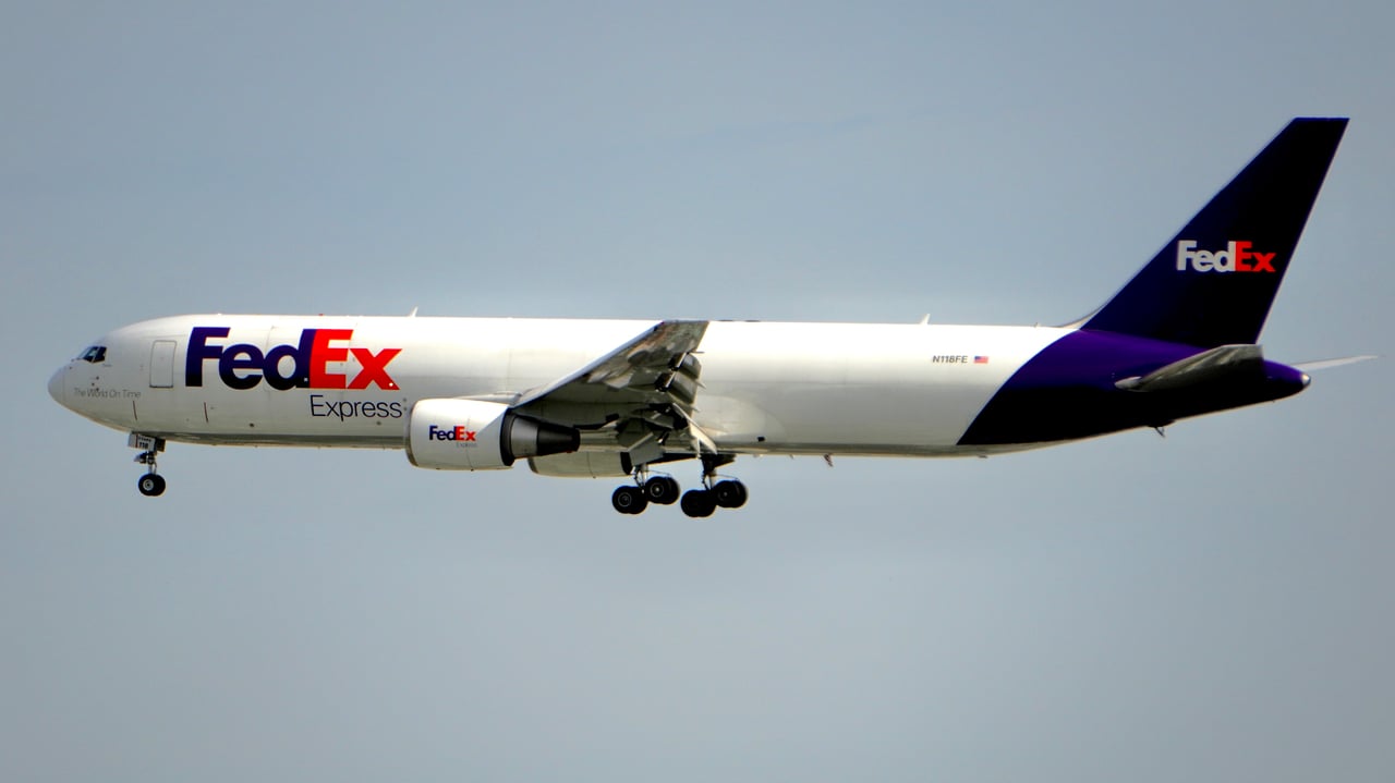 A FedEx cargo plane captured in mid-flight against a clear blue sky, showcasing air logistics.